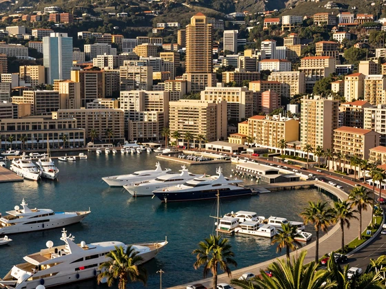 Panoramic view of Monaco harbor Port Hercules with luxury yachts and Mediterranean coastline at golden hour