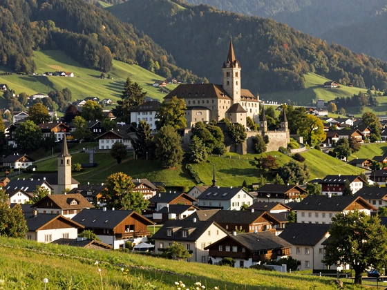 Vaduz Castle overlooking the Rhine Valley in Liechtenstein with alpine mountains and green meadows